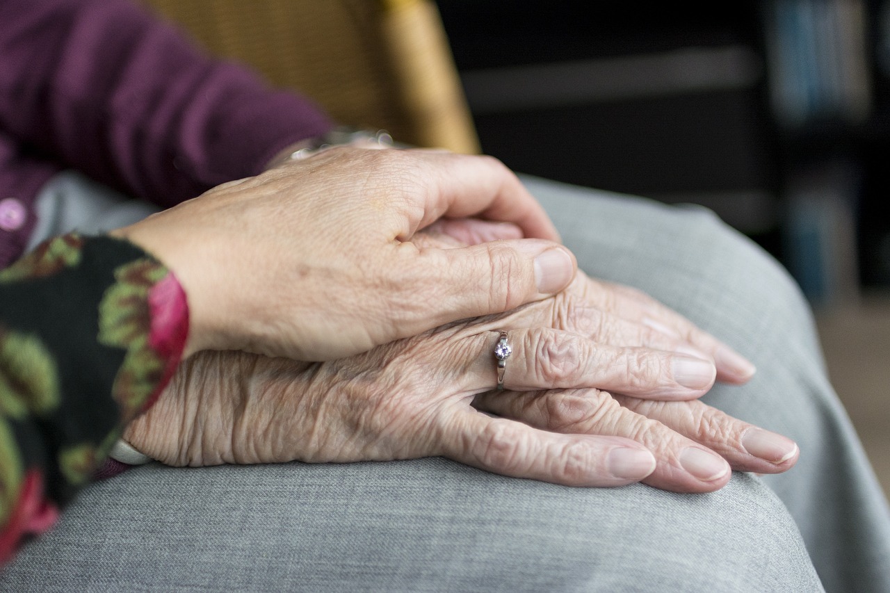 Two older people holding hands